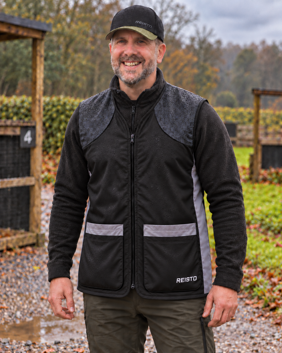 REISTO Apex Evo black softshell shooting vest worn outdoors over a long-sleeved layer.